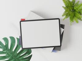 The tablet is placed on a white background and has green leaves. photo