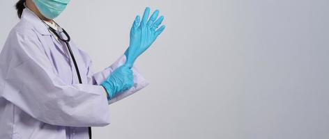 usando guantes. El médico asiático usa guantes de manos de nitrilo de goma azul. foto