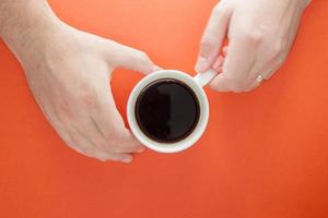 Male hands hold a cup of hot Americano coffee on a bright plain photo