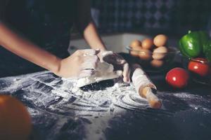 Las mujeres asiáticas preparando una pizza, en la mesa de la cocina foto