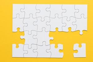 White cardboard jigsaw puzzles on yellow background photo