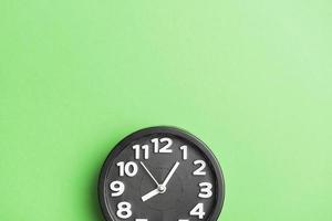 Reloj circular negro sobre fondo de pared verde foto