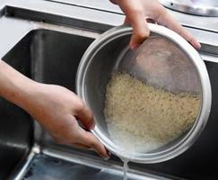 Lavar el arroz antes de cocinarlo, antes de cocinarlo en la olla arrocera. foto