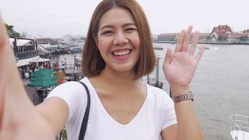 sorriso linda mulher asiática tirando selfies em um smartphone.