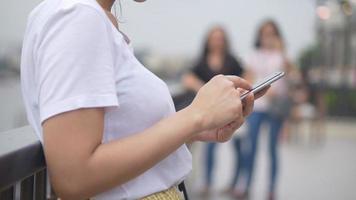 jonge Aziatische vrouw met behulp van smartphone buitenshuis openbare park.n close-up. video