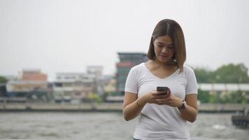 jovem mulher asiática usando smartphone. video