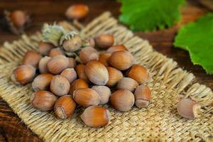 Hazelnuts on a wooden background with green leaves. photo