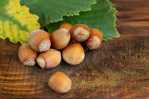 Hazelnuts on a wooden background with green leaves. photo