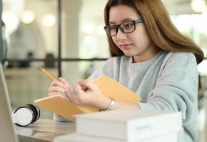 estudiante adolescente con gafas está estudiando en línea desde la computadora portátil. foto