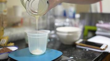 woman measure milk by weight to make bakery video