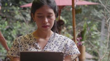 junge asiatische Frau mit Tablet im Café. Technologie sozialer Medien. video