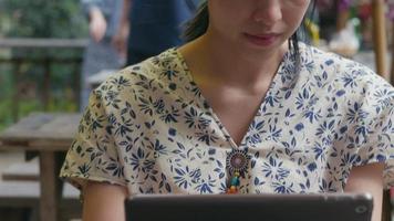 giovane donna asiatica che utilizza tablet nella caffetteria. social della tecnologia. video