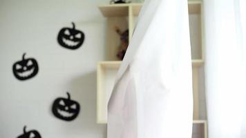 schattig Aziatisch meisje speelt in het gordijn in de kamer ingericht in halloween