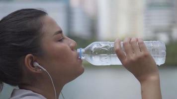 close-up portret jonge Aziatische vrouw runner water drinken na het hardlopen. sportvrouw met een gezonde levensstijl. video