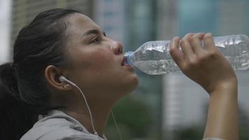 close-up portret jonge Aziatische vrouw runner water drinken na het hardlopen. sportvrouw met een gezonde levensstijl. video