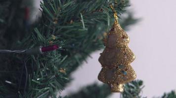 Golden box Christmas ornament hanging on a dry tree branch. 4K handheld shooting.