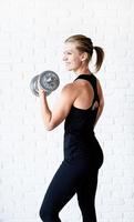 Mujer mostrando sus músculos entrenando con una mancuerna foto