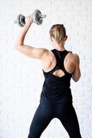 woman showing her back and arms muscles training with a dumbbell photo