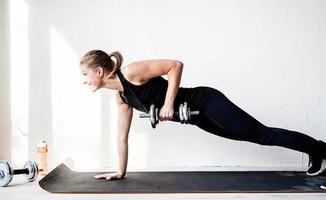 Mujer trabajando haciendo levantamientos con mancuernas entrenando su espalda y brazos foto