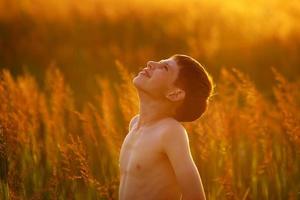 niño se encuentra entre la hierba del campo alto foto