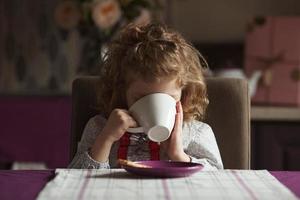 Little girl drinks tea photo