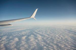 Wing of plane flying over cloudy in the blue sky photo