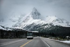 Bus driving on asphalt road with great snow mountain background