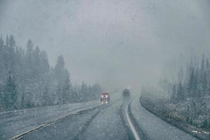 Car driving with poor visibility in blizzard with heavy snowing photo