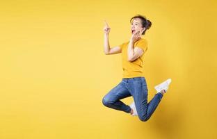 Full length portrait of cheerful girl jumping up isolated on yellow background photo