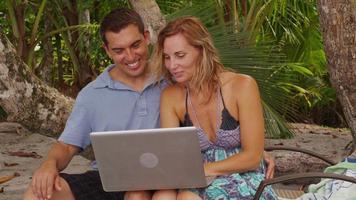 pareja en la playa usando laptop. filmado en rojo épico para una resolución de alta calidad de 4k, uhd, ultra hd. video