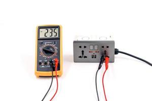 Using a digital meter to measure the voltage at a electric socket box on white background. photo