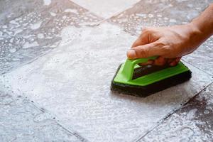 Cleaning the tiled floor with a plastic floor scrubber. photo