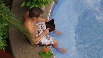 Man sitting on edge of hot tub using digital tablet. Shot on RED EPIC for high quality 4K, UHD, Ultra HD resolution. video