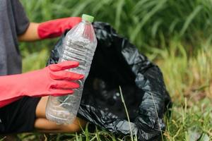 Boy man hand pick up plastic bottle in forest. Environment concept. photo