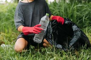 Boy man hand pick up plastic bottle in forest. Environment concept. photo