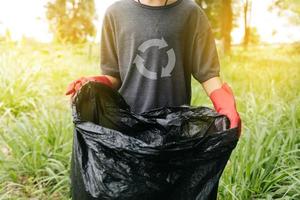 Boy man hand pick up plastic bottle in forest. Environment concept. photo