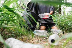 Boy man hand pick up plastic bottle in forest. Environment concept. photo
