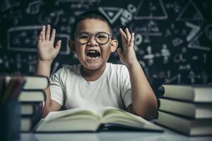 A boy with glasses sitting in the classroom reading photo
