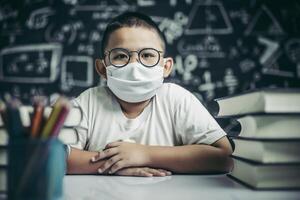 A boy with glasses sitting in the classroom studying photo