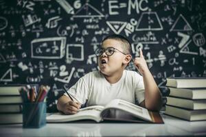 Los niños con gafas escriben libros y piensan en el aula. foto