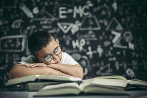 un niño con gafas estudiando y somnoliento. foto