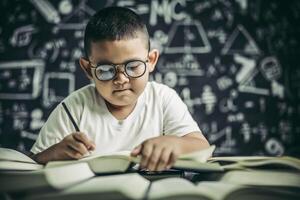 un niño con gafas hombre escribiendo en el aula foto