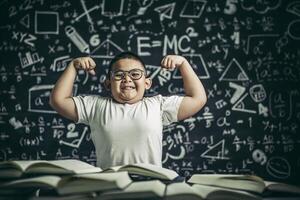 A boy with glasses sitting in the study and with both arms perpendicular photo