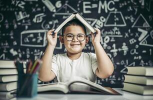 A boy with glasses studied and put a book on his head in the classroom. photo