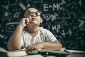 Boys with glasses write books and think in the classroom photo