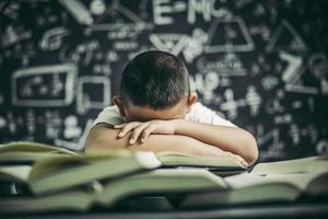 un niño con gafas estudiando y somnoliento. foto