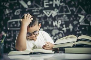 Los niños con gafas escriben libros y piensan en el aula. foto