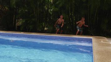 dois meninos pulam na piscina, movimento lento. filmado em vermelho épico para alta qualidade 4k, uhd, resolução ultra hd. video