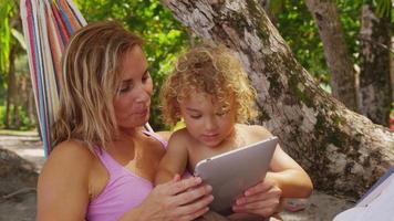 mère et fils dans un hamac à l'aide d'une tablette numérique, costa rica. tourné sur red epic pour une résolution 4k, uhd, ultra hd de haute qualité. video