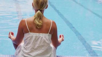 vrouw mediteren bij het zwembad. geschoten op rood episch voor hoge kwaliteit 4k, uhd, ultra hd-resolutie. video